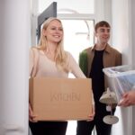 Group Of College Student Carrying Boxes Moving Into Accommodation Together